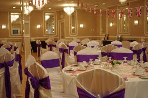 un salón de banquetes con mesas blancas y sillas moradas en Causeway Bay Hotel, en Sparwood (British Columbia)