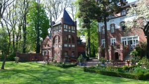 an old brick building with a tower in a yard at Pension Villa Fortuna in Lübben