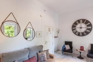 a living room filled with furniture and a clock at Apartamentos Plaza Pilatos in Seville