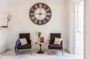 a clock on a wall above two chairs and a table at Apartamentos Plaza Pilatos in Seville