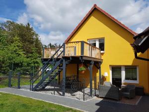 Casa amarilla con escalera y balcón. en Ferienwohnung Gleißner, en Garz
