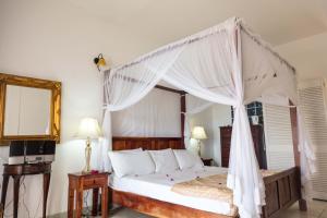 una camera da letto con un letto a baldacchino di Bacolet Beach Club a Scarborough