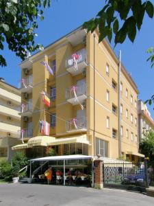 un grande edificio giallo con bandiere appese ad esso di Hotel Giumer a Rimini