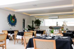 Hotel Maui Maresias في ماريسياز: غرفة طعام مع طاولات وكراسي سوداء