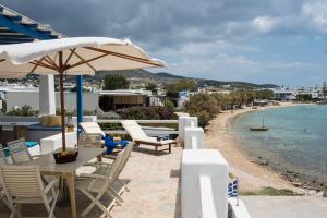 a patio with chairs and an umbrella and a beach at Evita Apartments in Aliki