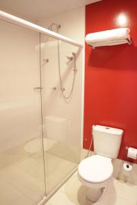 a bathroom with a toilet and a glass shower at ibis Styles Sao Mateus in São Mateus