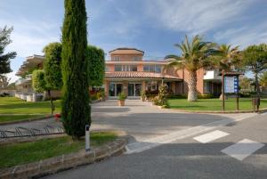 een groot huis met een palmboom ervoor bij Villaggio Turistico La Cecinella in Marina di Cecina