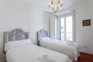 マドリードにあるExclusivo 3 dormitorios Plaza Mayorのベッドルーム1室(ベッド2台、シャンデリア付)