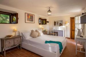 a bedroom with a white bed and a kitchen at B&B Borgo Vera in Manciano