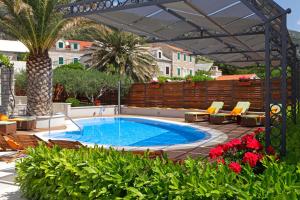a swimming pool with chairs and a pergola at Apartments Diana - NEW heated pool in Bol