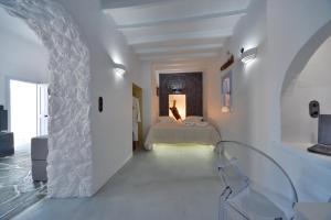 a white bedroom with a bed and a window at AMO Folegandros in Karavostasi