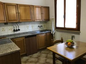 una cocina con armarios de madera y una mesa con un bol de fruta en La Casina, en Case Fortullino