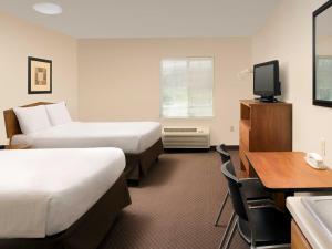 ベルビューにあるWoodSpring Suites Omaha Bellevue, an Extended Stay Hotelのベッド2台、デスク、テレビが備わるホテルルームです。