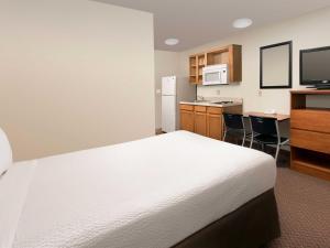 ベルビューにあるWoodSpring Suites Omaha Bellevue, an Extended Stay Hotelのベッドとキッチン付きのホテルルーム