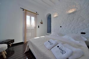 a white bedroom with a bed with white sheets and pillows at AMO Folegandros in Karavostasi