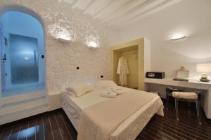 a bedroom with a bed and a desk in it at AMO Folegandros in Karavostasi