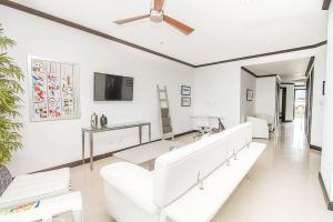 un soggiorno con mobili bianchi e TV a schermo piatto di Best in Jaco Condos at Diamante del Sol a Jacó
