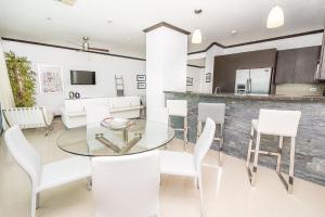 a kitchen and dining room with a glass table and white chairs at Best in Jaco Condos at Diamante del Sol in Jacó