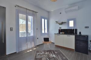 a room with a kitchen with a counter and a tv at AMO Folegandros in Karavostasi