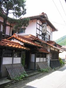 um edifício com dois bancos à sua frente em Noren Yado Meigetsu em Tsuwano