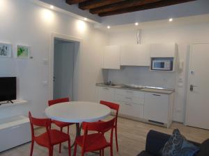 Una cocina con una mesa blanca y sillas rojas. en Ca' Sansovino, en Venecia