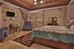 a bedroom with a bed and a stone wall at Guzide Cave Hotel in Göreme