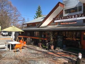 a restaurant with a table and an umbrella in front of it at 乗鞍高原の宿テンガロンハットB&BTengallonhat in Matsumoto