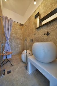 a bathroom with a large white sink and a tub at AMO Folegandros in Karavostasi