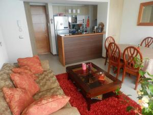 sala de estar con sofá, mesa y cocina en Departamento Resort Lagunas del Mar, en La Serena