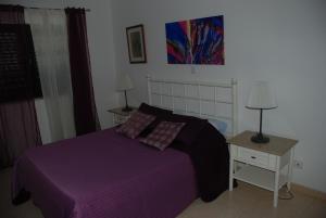 een slaapkamer met een paars bed en 2 nachtkastjes bij Terraço e Mar in Alvor
