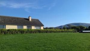 a house with a hedge in front of a green field at Avondale in Sligo