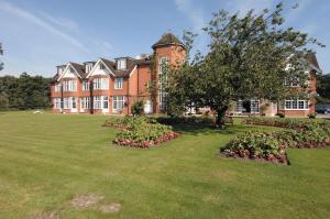 a large red brick building with a tree in the yard at Grovefield House Hotel in Slough