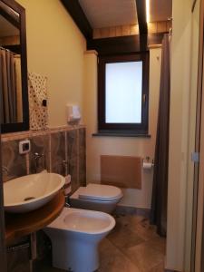 a bathroom with a sink and a toilet and a window at Lily house in Gravina di Catania