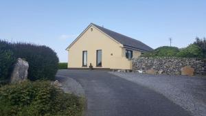 una casa blanca con una pared de piedra junto a una carretera en Avondale en Sligo