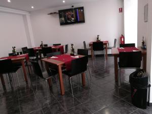 een restaurant met tafels en stoelen en een tv aan de muur bij Albergaria O Professor in Santa Cruz