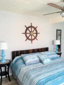 a bed with a wooden head board with a ship wheel on the wall at Capri Beach Hotel in Corpus Christi