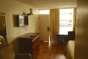a hotel room with a bed and a tv and a dresser at Sea Cove Motel Ocean City in Ocean City
