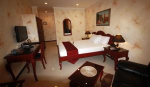 um quarto com uma cama, uma secretária e uma televisão em Hotel Royal Amsterdam em Angeles