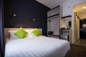 a bedroom with a large white bed with green pillows at Manhattan Hotel Ipoh in Ipoh