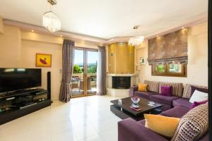 sala de estar con sofá púrpura y TV en Villa Flabellina, en Adelianos Kampos