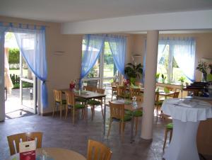 a dining room with tables and chairs and windows at Hotel Zum Grünen Tor in Hoppegarten