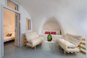 a white bedroom with a bed and two chairs at Artia Mansion in Oia