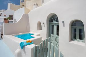a white house with a swimming pool and a door at Artia Mansion in Oia