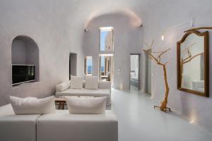 a living room with white furniture and a mirror at Ammos Oia Mansion in Oia
