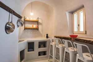 a kitchen with a bar with white stools at Ammos Oia Mansion in Oia