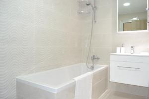 a white bathroom with a tub and a sink at Marianna Hotel Apartments in Limassol
