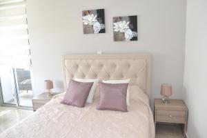 a bedroom with a white bed with two pink pillows at Marianna Hotel Apartments in Limassol