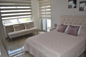 a bedroom with a bed and a chair and windows at Marianna Hotel Apartments in Limassol