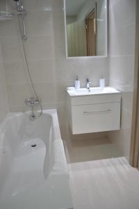 a white bathroom with a sink and a bath tub at Marianna Hotel Apartments in Limassol