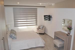 a bedroom with a bed and a chair and a window at Marianna Hotel Apartments in Limassol